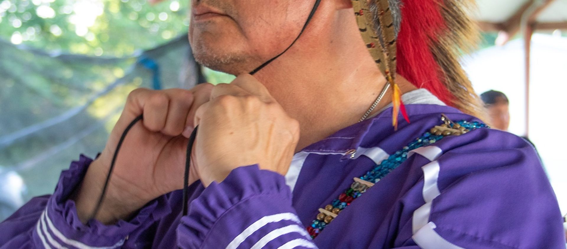 Wahzhazhe man ties on his broach during the Hominy Inlonshka (2021).
