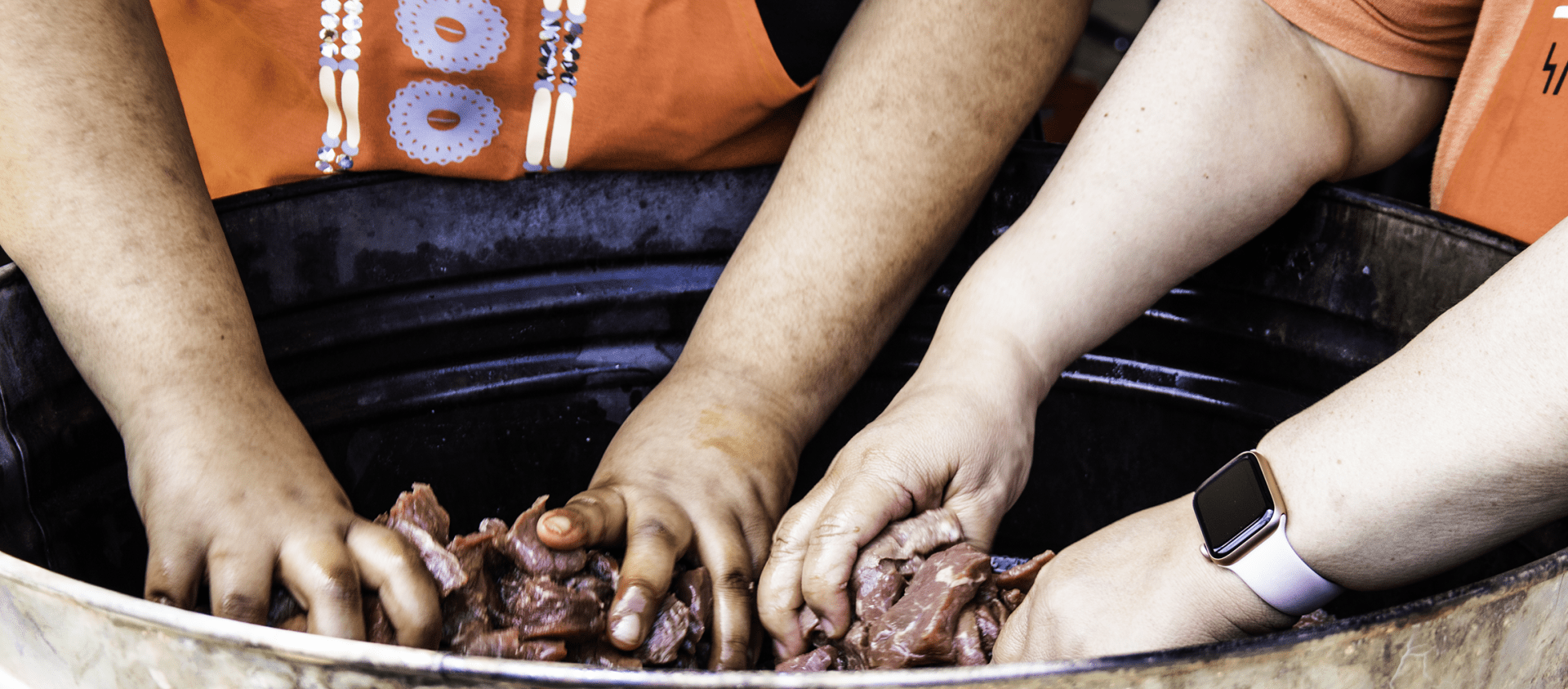 Wahzhazhe cooks preparing meat to make meat gravy, a traditional dish. Squeezing the meat removes the blood and makes it more flavorful. 
