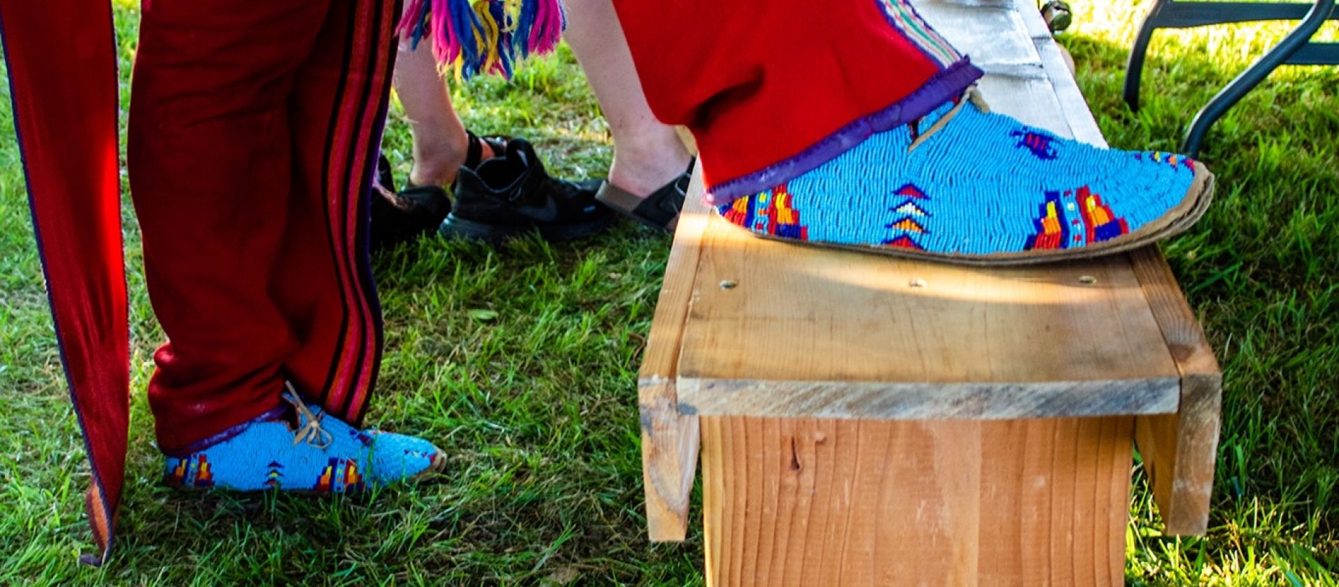 Wahzhazhe man puts on bells over finger woven garters with broadcloth leggings and fully beaded moccasins. 